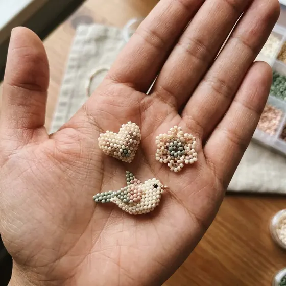 Beaded hearts and a small bird resting in a palm